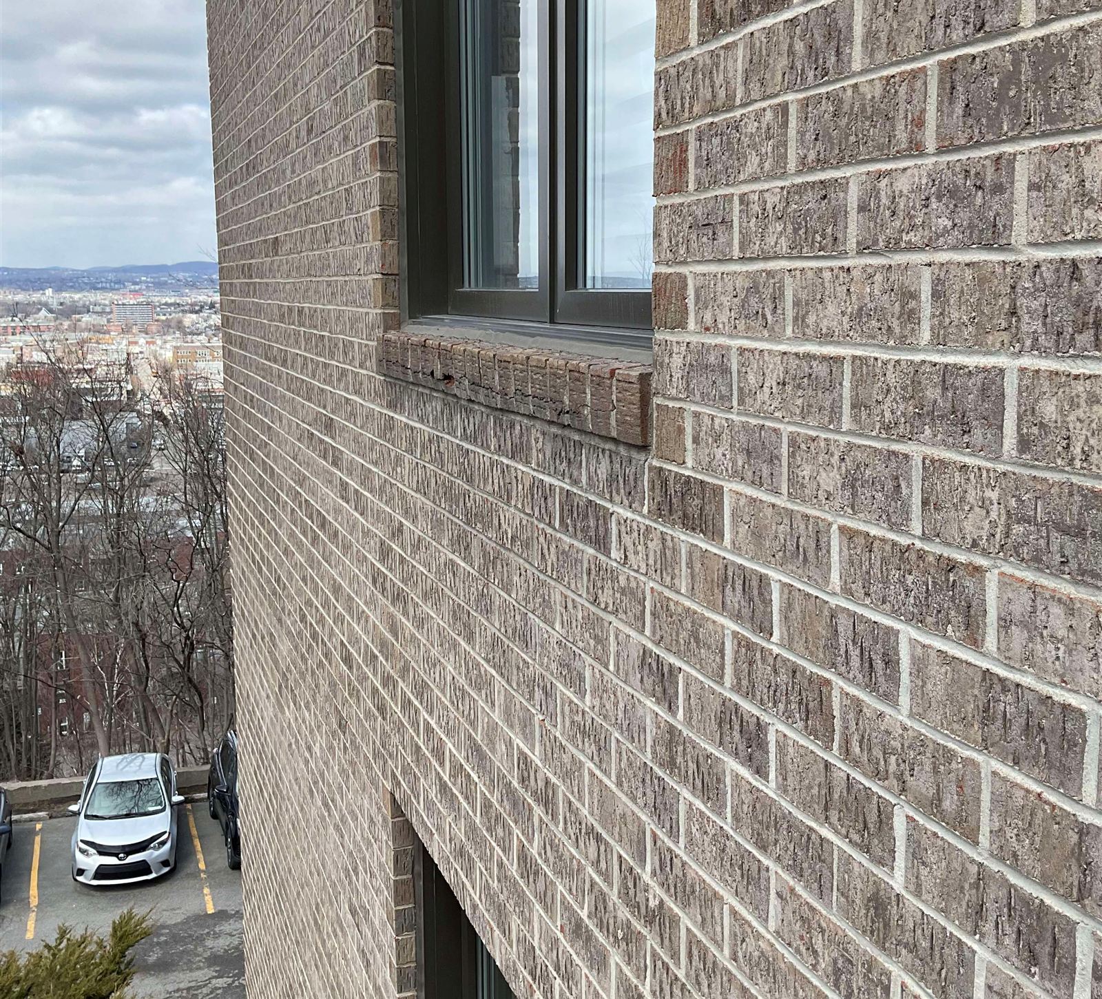 Façade de brique d’un immeuble en hauteur, photographiée par un cordiste en cours d’inspection